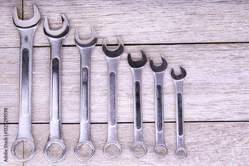 Obraz na płótnie Set of metallic wrenches arranged in size order on a rustic wooden background. Ideal for themes related to mechanics, construction, DIY projects, and professional toolkits in industrial settings. w salonie