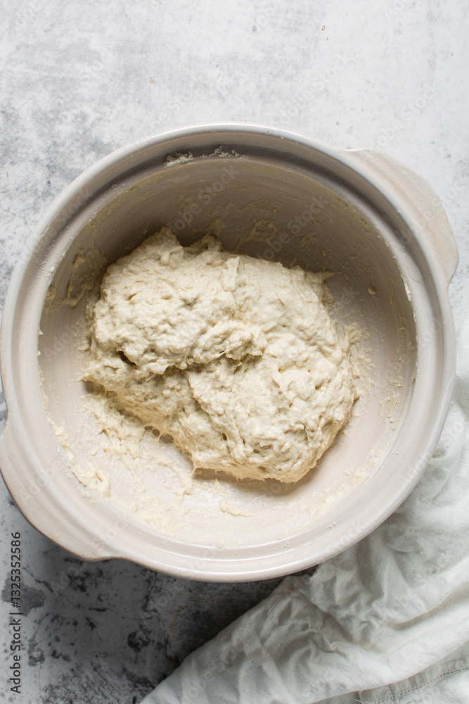 Overhead view of focaccia dough on a white marble countertop, top view of homemade focaccia bread dough in a claypot, process of making focaccia Overhead view of focaccia dough on a white marble countertop, top view of homemade focaccia bread dough in a claypot, process of making focaccia