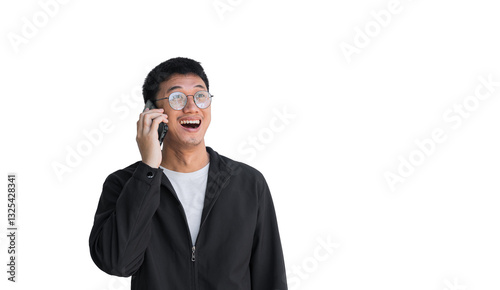 Young Asian man in his 20s wearing glasses and a black coat talking on the phone with an excited and happy expression, standing alone on a white background. Long-distance communication concept.