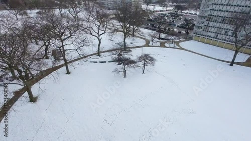 Aerial FPV drone footage of local urban Chicago park during the winter moving swiftly through the snow and playground area into the sprawling cityscape.  