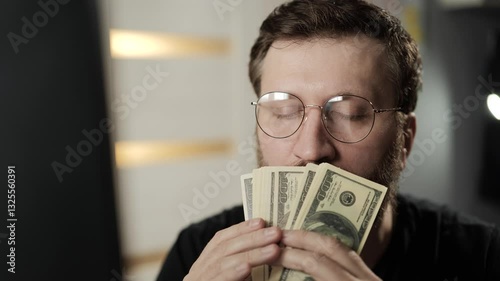 Fee, success, income concept. Happy man in glasses holds US dollars in his hands and rejoices in luck, inhales smell of money