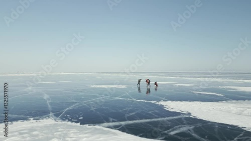 Tourists with a backpack is skating on the blue transparent ice of the endless lake Baikal. The concept of unique winter places of the earth