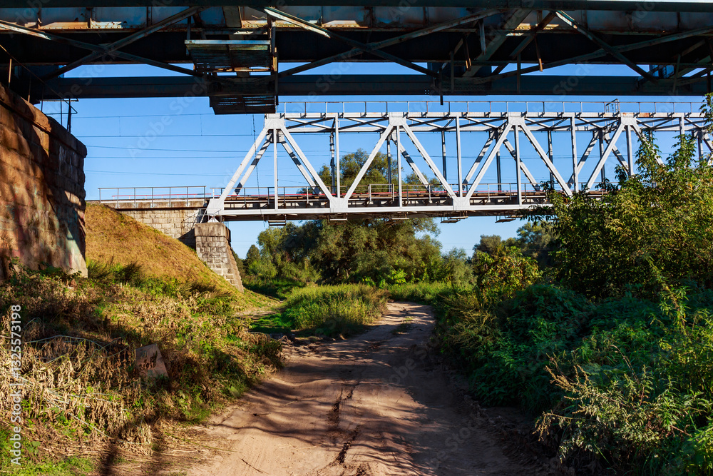 Obraz premium Country road passing under iron railway bridges