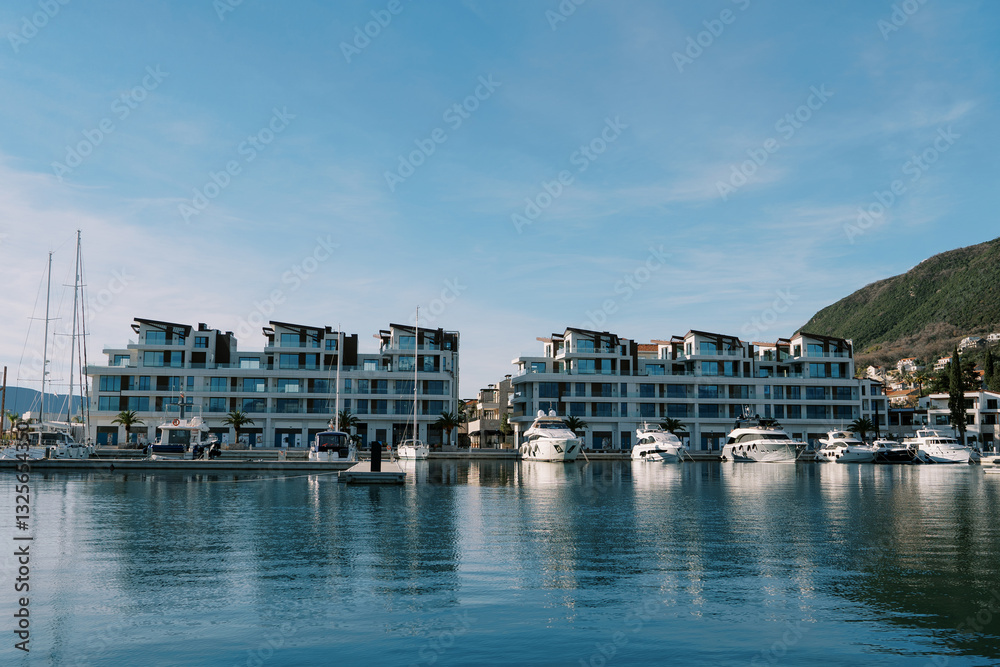 Sailing yachts stand off the coast with high-rise buildings at the foot of the mountains Sailing yachts stand off the coast with high-rise buildings at the foot of the mountains