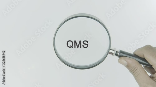 QMS (Quality Management System) highlighted by a magnifying glass on a white background, symbolizing the structured approach to ensuring quality standards, continual improvement, and consistent produc