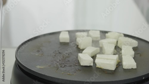 Halloumi cheese pieces on frying plate close up. Cooking process