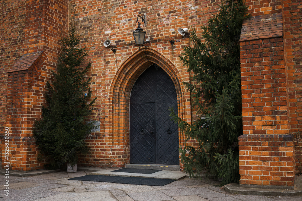 Historic brick church entrance framed by evergreen trees in Warsaw. Historic brick church entrance framed by evergreen trees in Warsaw.