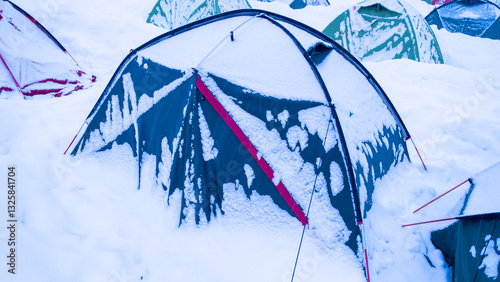 Colorful camping tents covered in snow after a snowstorm.