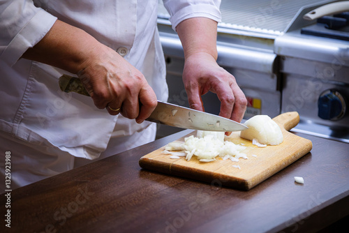 Chef Chopping Onion on Wooden Cutting Board in a Professional Kitchen