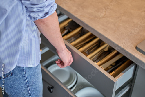 Obraz na płótnie Person opens a kitchen drawer with various utensils in wooden cutlery tray. Woman opening kitchen cabinet. Concept of home organization and functionality interior w salonie