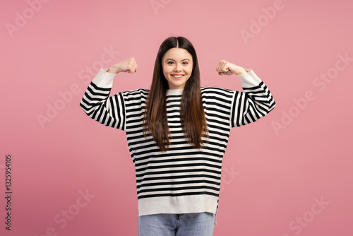 Foto Attractive, smiling girl showing strength and confidence on pink background