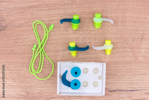Close up of ear protection plugs from water and noise, suitable for swimming, snorkeling and diving. Rubber earplugs of different sizes and colors isolated on wooden background