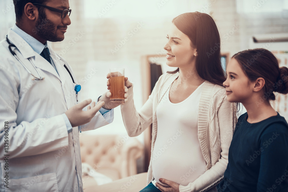 Fototapeta premium Indian doctor seeing patients in office. Doctor is giving mixture to pregnant woman with daughter.