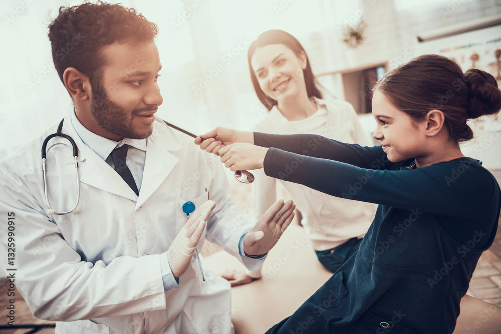 Indian doctor seeing patients in office. Daughter is pulling stethoscope. Indian doctor seeing patients in office. Daughter is pulling stethoscope.