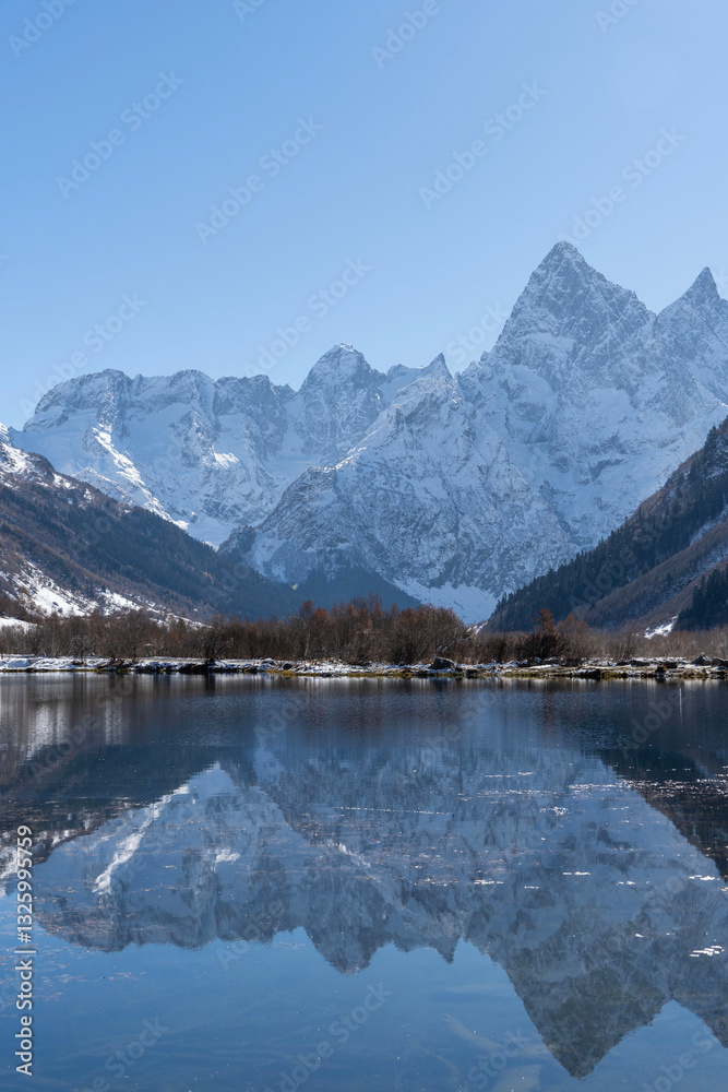 Fototapeta premium Dombay, Karachay-Cherkessia. Teberda National Park. Lake Tumanly-Gel or Tumanly-Kol (Misty Lake) is in valley of Gonachkhir River. Snowy peaks of Mount Chotcha are reflected in lake as in mirror.