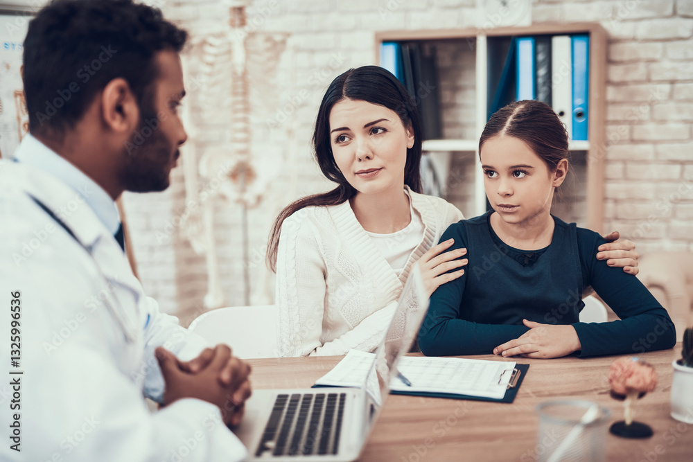 Indian doctor seeing patients in office. Doctor is showing clipboard to mother and daughter. Indian doctor seeing patients in office. Doctor is showing clipboard to mother and daughter.