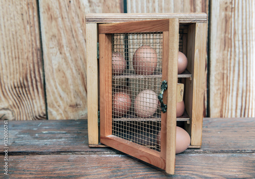 chicken eggs  in a decorative box on a table in front of a wooden wall  backg...