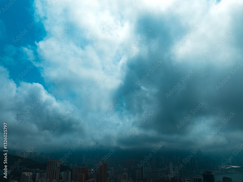 Aerial panorama of Hong Kong city under a dramatic sky filled with dense clouds. A high-angle view showcases the urban landscape and skyline. Aerial panorama of Hong Kong city under a dramatic sky filled with dense clouds. A high-angle view showcases the urban landscape and skyline.