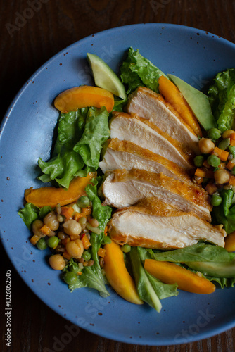 juicy fried chicken with vegetables and sweet peaches on a blue plate