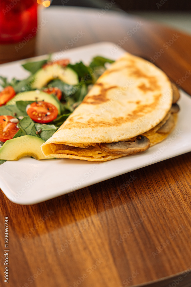 Tortilla with champignons with salad in a square white plate. Tortilla with champignons with salad in a square white plate.