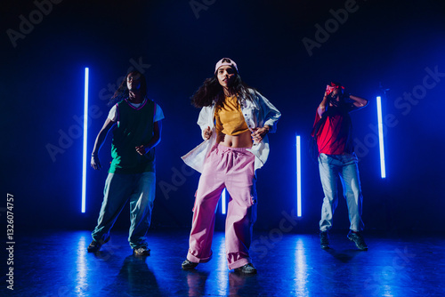 Group of hip hop dancer dancing together in a moody studio with tube neon lights.