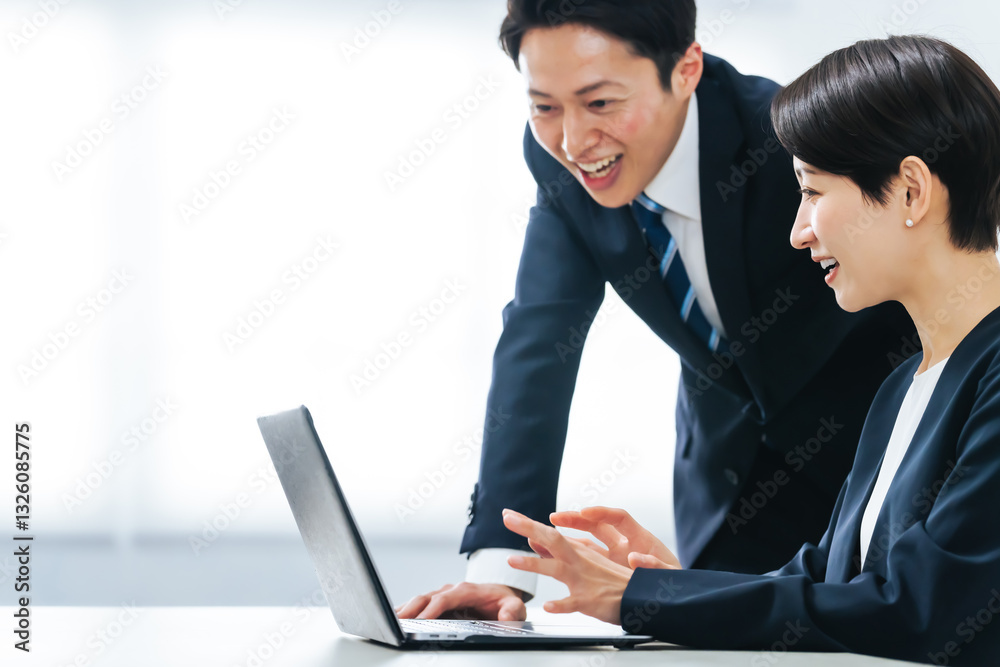 オフィスでノートパソコンを見ながら会話する男女ビジネスパーソンのグループ