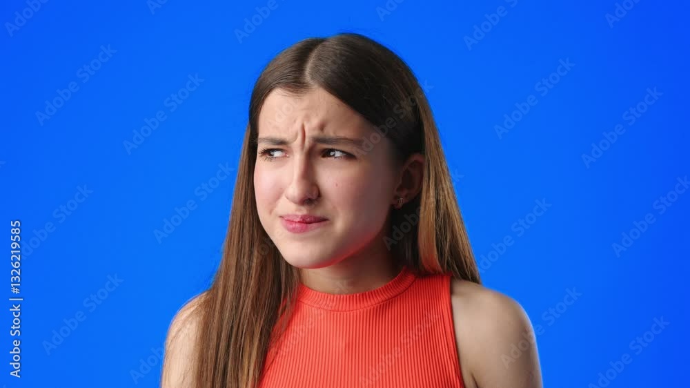Girl with a confused expression on a bright blue background during a discussion or interview Girl with a confused expression on a bright blue background during a discussion or interview