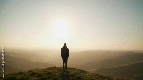 A beautiful silhouette of a person standing alone on a hilltop, watching the sunrise in a moment of hope and contemplation.