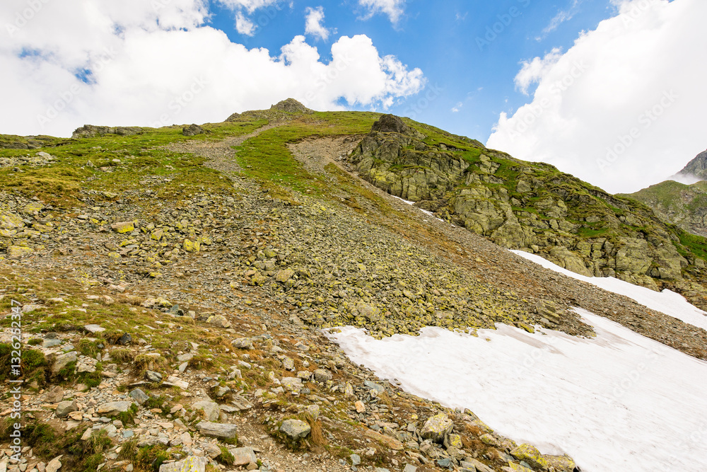 landscape with mountain and blue sky with clouds. steep hill with stones and grass. beautiful nature of romania in summer