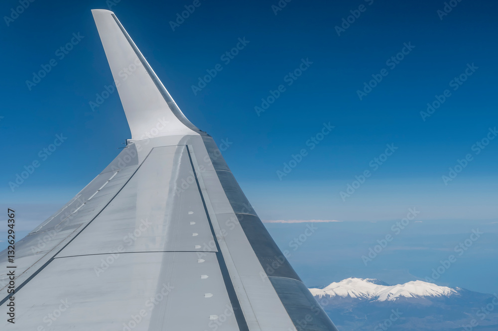 The wing of a plane in flight as it flies over the snow-capped mountains on the border between Greece and Albania The wing of a plane in flight as it flies over the snow-capped mountains on the border between Greece and Albania