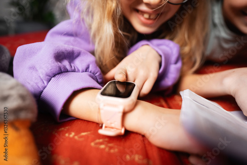 Close-up happy little girl talking on video chat using kids smartwatch. Video call on smart watch. Child using smartwatch indoor, talking with friends. Concept of technology, communication, family. 