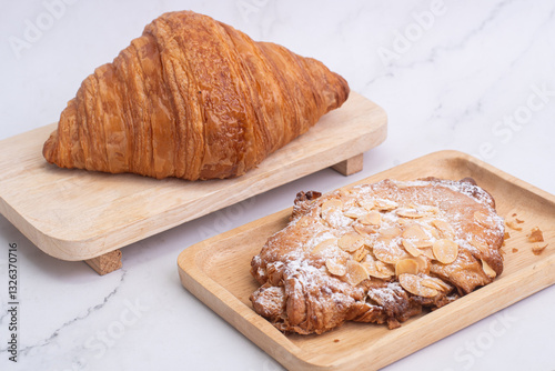 almond croissants on wooden cutting board on white marble background