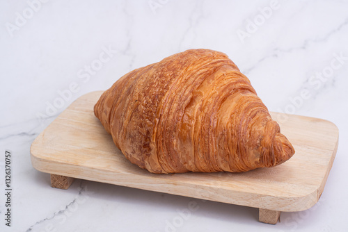 plain croissants on wooden cutting board on white marble background
