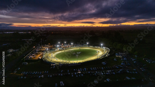 Aerial view of vibrant motor racing speedway under twilight with illuminated cars and enthusiastic crowd, Richmond, Tasman, New Zealand.