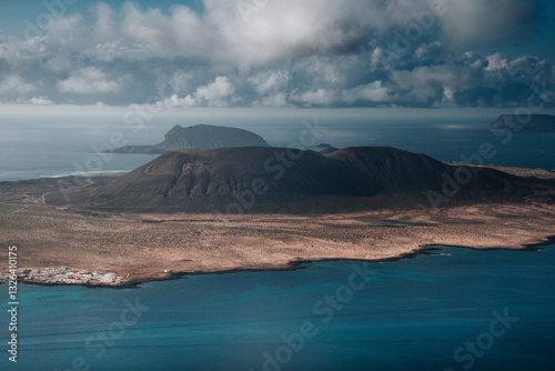 Aerial view of volcanic island landscape with rugged terrain and serene ocean, Las Hoyas, Lanzarote, Canary Islands, Spain.