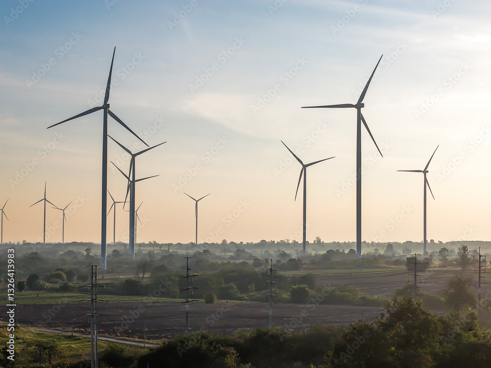 Obraz premium Hundred of wind turbines standing in agricultural rural field generating green ecological energy at Huay Bong, Thailand