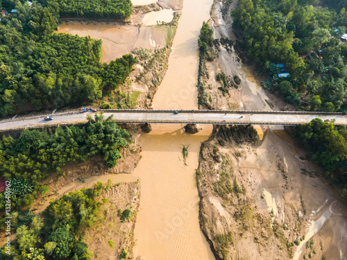 Aerial view of a beautiful bridge over a scenic river surrounded by lush forest, Jhenaigati, Sherpur, Bangladesh. photo