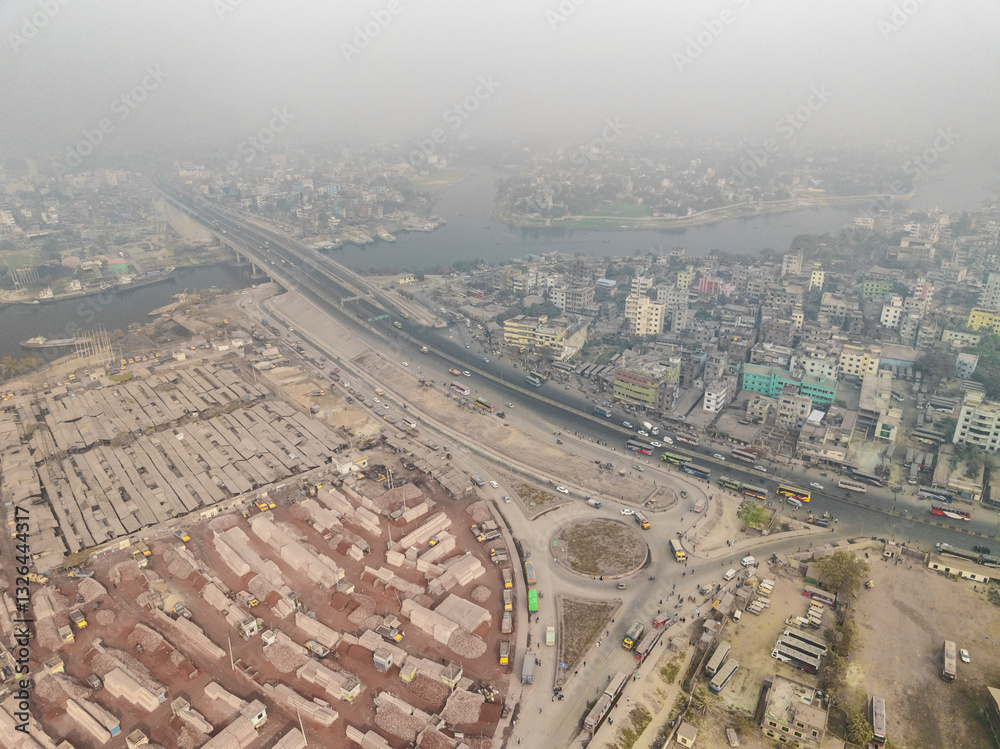 Aerial view of bustling urban landscape with dense buildings and busy roads alongside a river and bridge, Darus Salam Thana, Dhaka, Bangladesh. Aerial view of bustling urban landscape with dense buildings and busy roads alongside a river and bridge, Darus Salam Thana, Dhaka, Bangladesh.