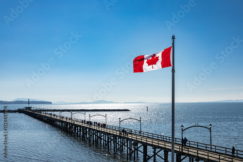 White Rock city pier in the dusk with flying Flag of Canada, British Columbia, Canada.