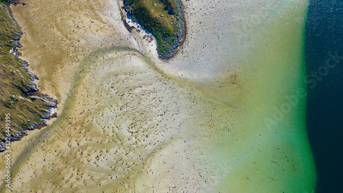 Aerial view of serene low tide patterns of water, sand, and soil along the picturesque coastline, Flakstad, Lofoten, Norway. photo