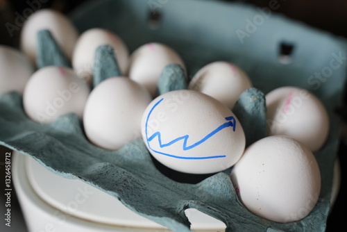 Box of white eggs with 1 eggs marked with a increasing line graph, depicting high egg prices. Egg inflationary prices concept. Expensive eggs. Bird flue concept