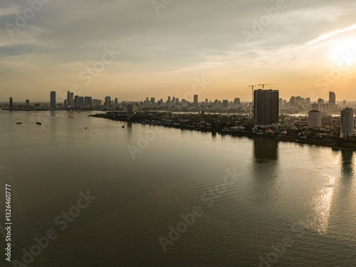 Aerial view of tranquil sunset skyline over the river with modern skyscrapers reflecting on the water, Chroy Changvar, Phnom Penh, Cambodia.