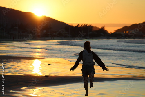 mulher correndo na beira da praia no nascer do sol 