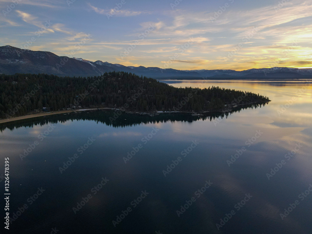 Aerial view of serene winter sunset over tranquil lake reflecting majestic mountains and silhouetted forest, Glenbrook, Nevada, United States. Aerial view of serene winter sunset over tranquil lake reflecting majestic mountains and silhouetted forest, Glenbrook, Nevada, United States.