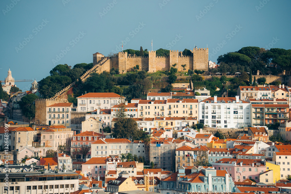 Aerial view of Castelo de Sao Jorge surrounded by colorful rooftops and residential buildings on a sunny day, Encarnacao, Lisbon, Portugal. Aerial view of Castelo de Sao Jorge surrounded by colorful rooftops and residential buildings on a sunny day, Encarnacao, Lisbon, Portugal.