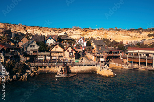 Aerial view of the picturesque Popeye Village with charming old town houses along the scenic coastline and cliffs, Mellieha, Malta.