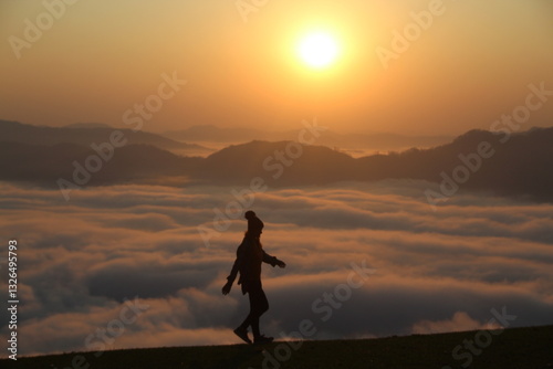 silhueta de mulher em topo de montanha com mar de nuvens e sol nascendo no horizonte - foto tirada no morro são bernardo em rio dos cedros, santa catarina  photo