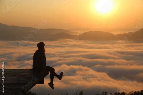 silhueta de mulher em topo de montanha com mar de nuvens e sol nascendo no horizonte - foto tirada no morro são bernardo em rio dos cedros, santa catarina  photo