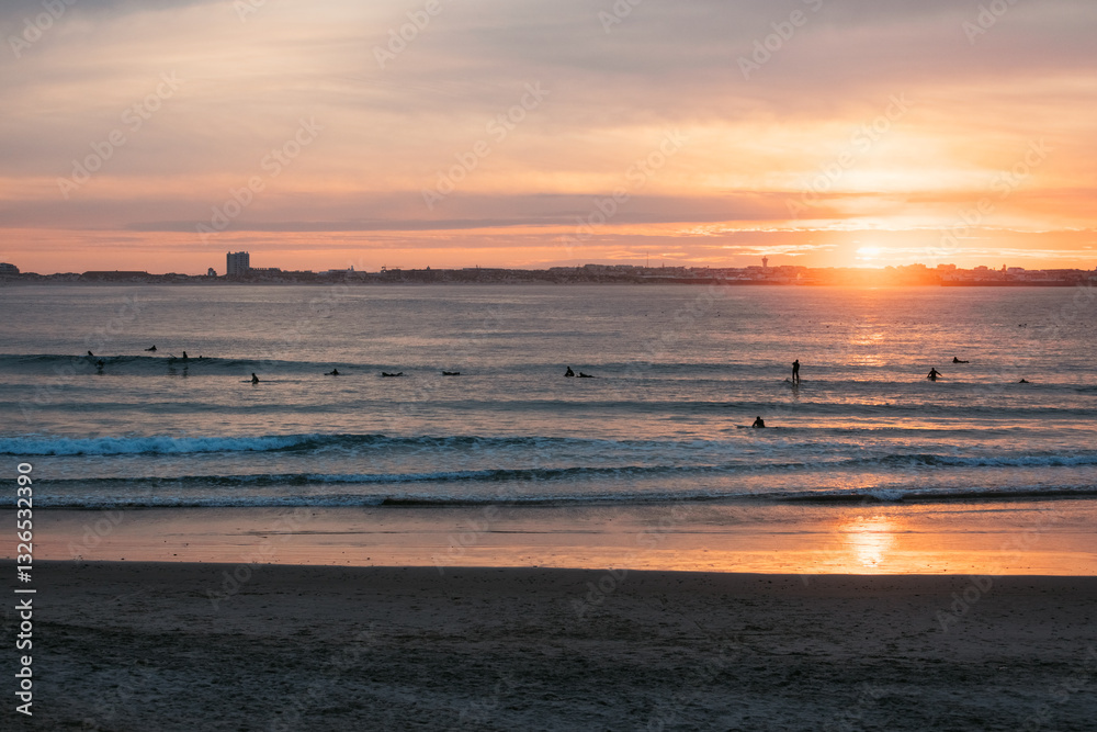 Surfers float on gentle waves under a glowing sunset in Baleal Surfers float on gentle waves under a glowing sunset in Baleal