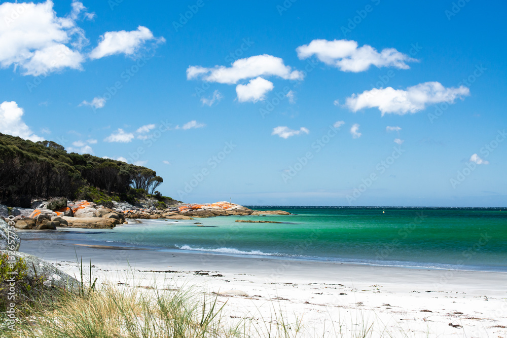 Picturescue white beach with orange rocky point, turquoise sea and blue sky with fluffy white clouds Picturescue white beach with orange rocky point, turquoise sea and blue sky with fluffy white clouds